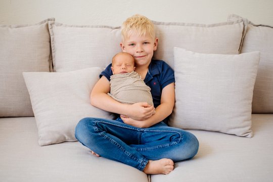 Großer Bruder und Baby auf dem Sofa