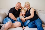 Vater Mutter großer Bruder und neugeborenes Baby kuscheln auf dem Sofa