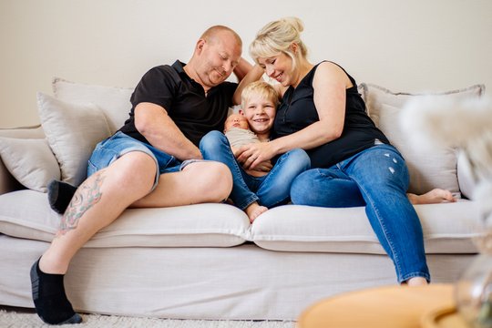 Vater Mutter großer Bruder und neugeborenes Baby kuscheln auf dem Sofa