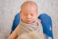 Porträt von einem Baby das in den Händen der Mutter liegt