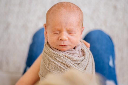 Porträt von einem Baby das in den Händen der Mutter liegt