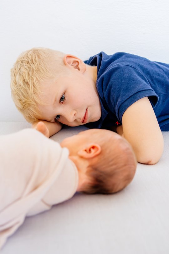 großer Bruder schaut Baby beim schlafen zu
