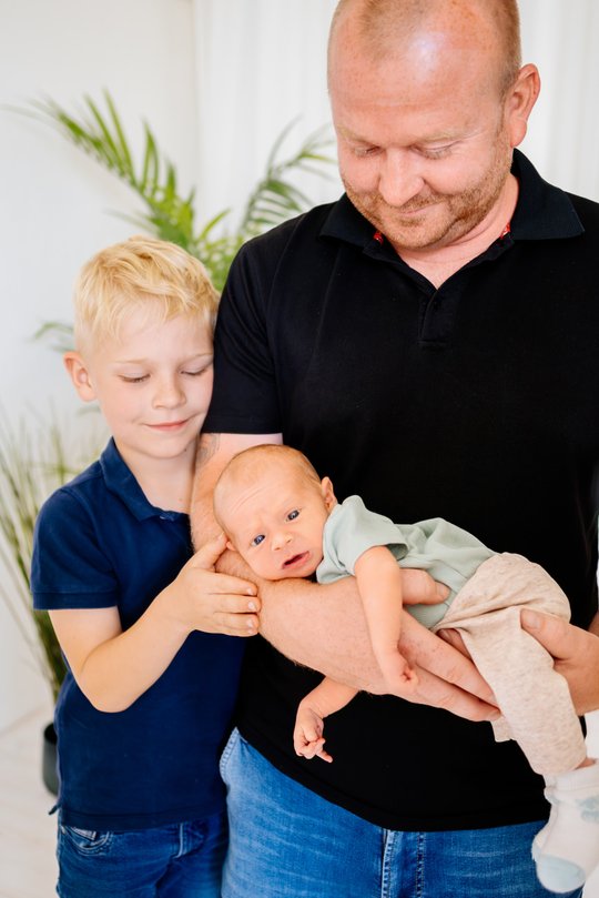 Vater mit Baby auf dem Arm und großem Sohn