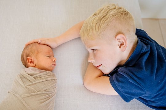 Großer Bruder schaut Baby beim schlafen zu